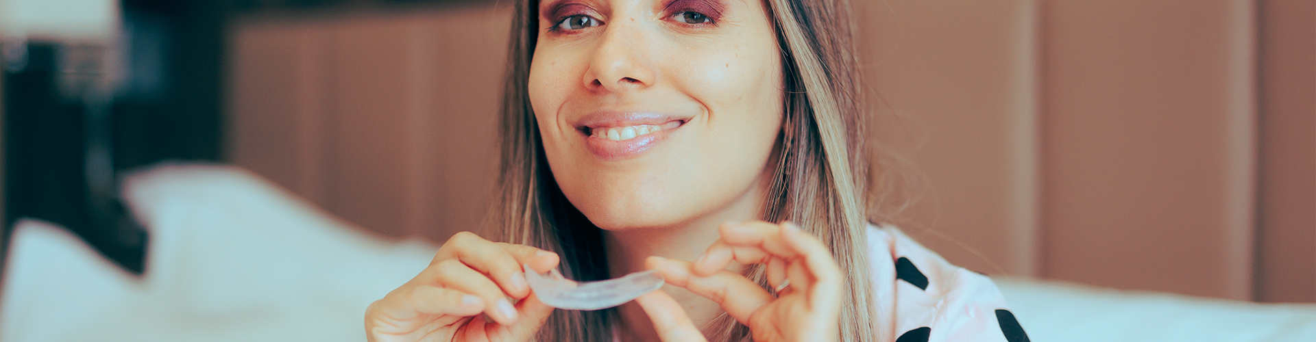 smiling woman holding clear aligners